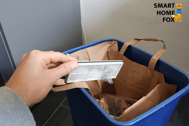 Der HEPA-Filter des Roborock S7 wird über einem Mülleimer ausgeklopft.